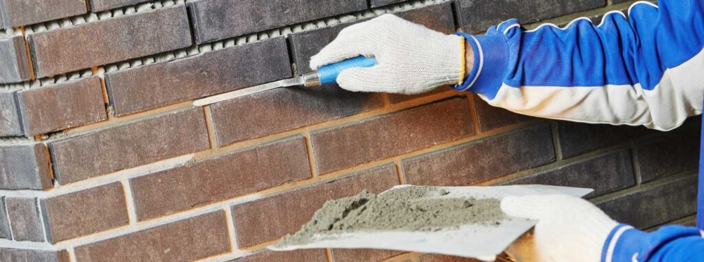 Masonry worker applying mortar to brick wall