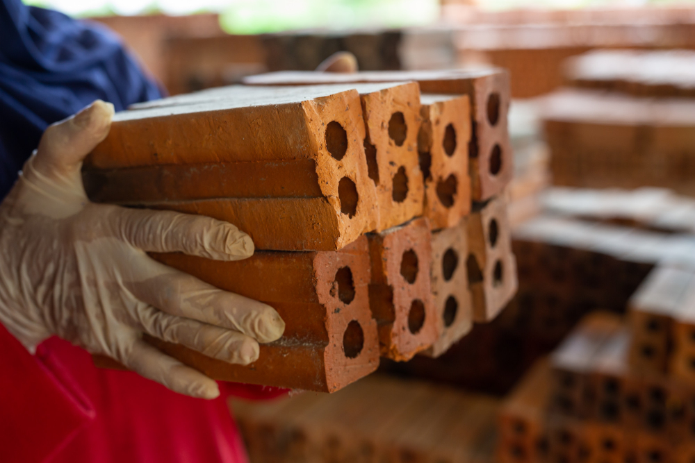 Person carrying stack of perforated clay bricks