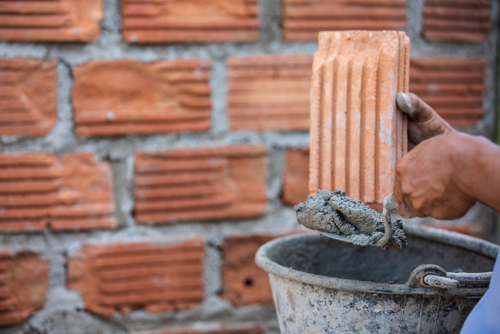 Worker applying mortar to red clay bricks