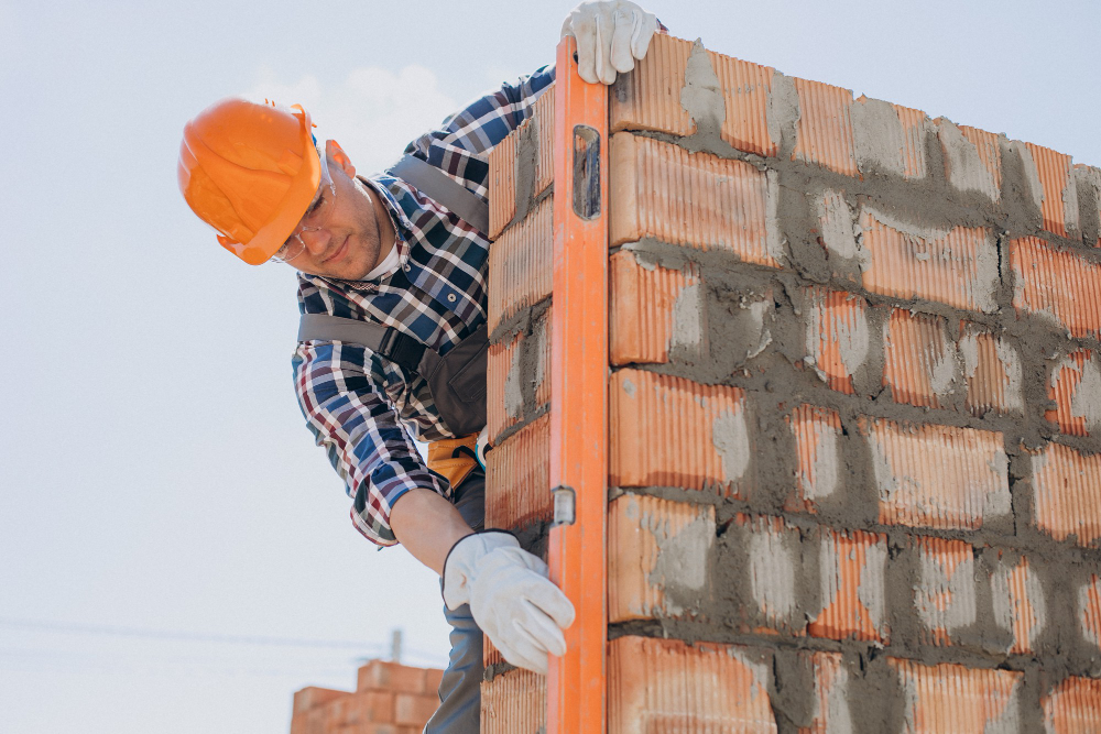 Construction worker leveling a brick wall carefully